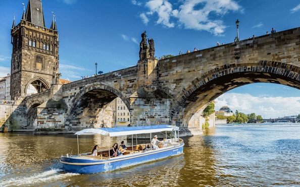 Sightseeing cruise boat passing under Charles Bridge in Prague's Devils Channel.