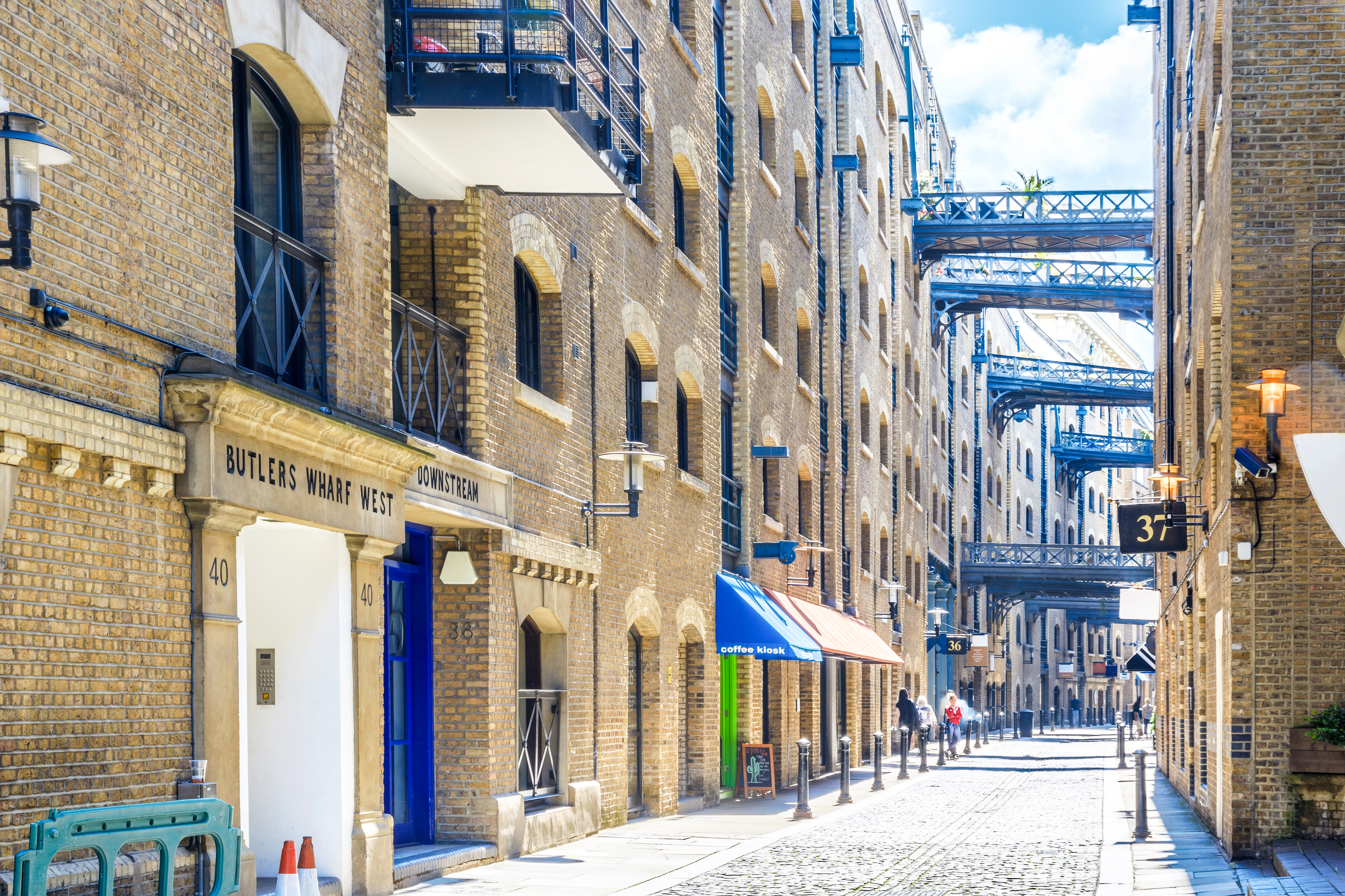 Shad Thames street view with historic brick buildings and overhead walkways in London.