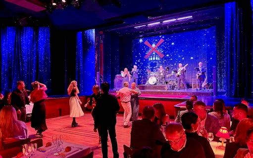 Guests dancing at Moulin Rouge pre-show in Paris with live band on stage.