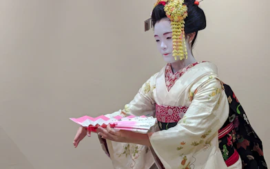 Maiko in traditional kimono performing with a fan in Kyoto, Japan.