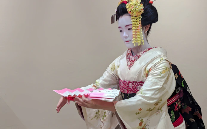 Maiko in traditional kimono performing with a fan in Kyoto, Japan.
