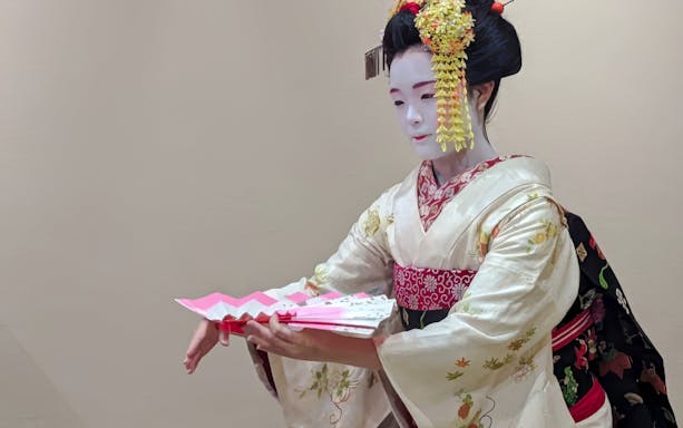 Maiko in traditional kimono performing with a fan in Kyoto, Japan.