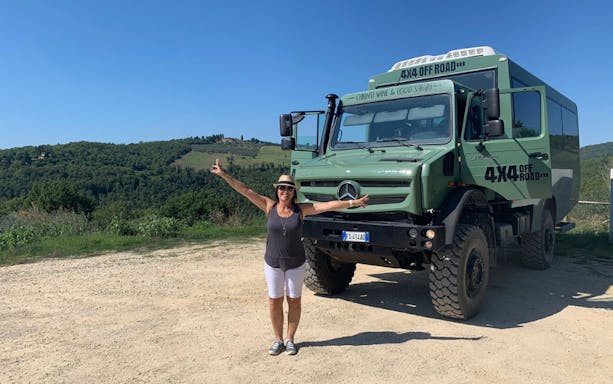 4x4 vehicle on Chianti wine tour with woman posing, Tuscany hills in background.