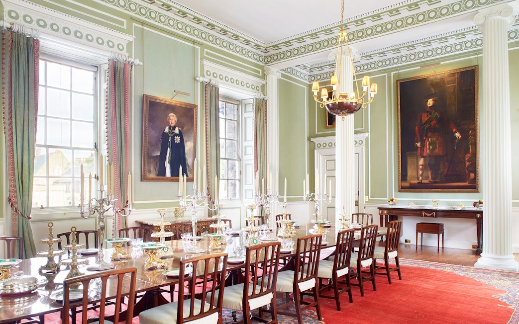 Dining room inside Palace of Holyroodhouse, Edinburgh, with ornate decor and portraits.
