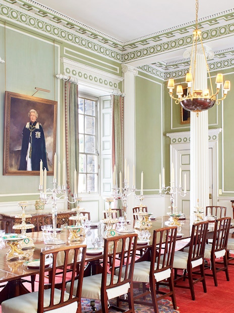 Dining room inside Palace of Holyroodhouse, Edinburgh, with ornate decor and portraits.