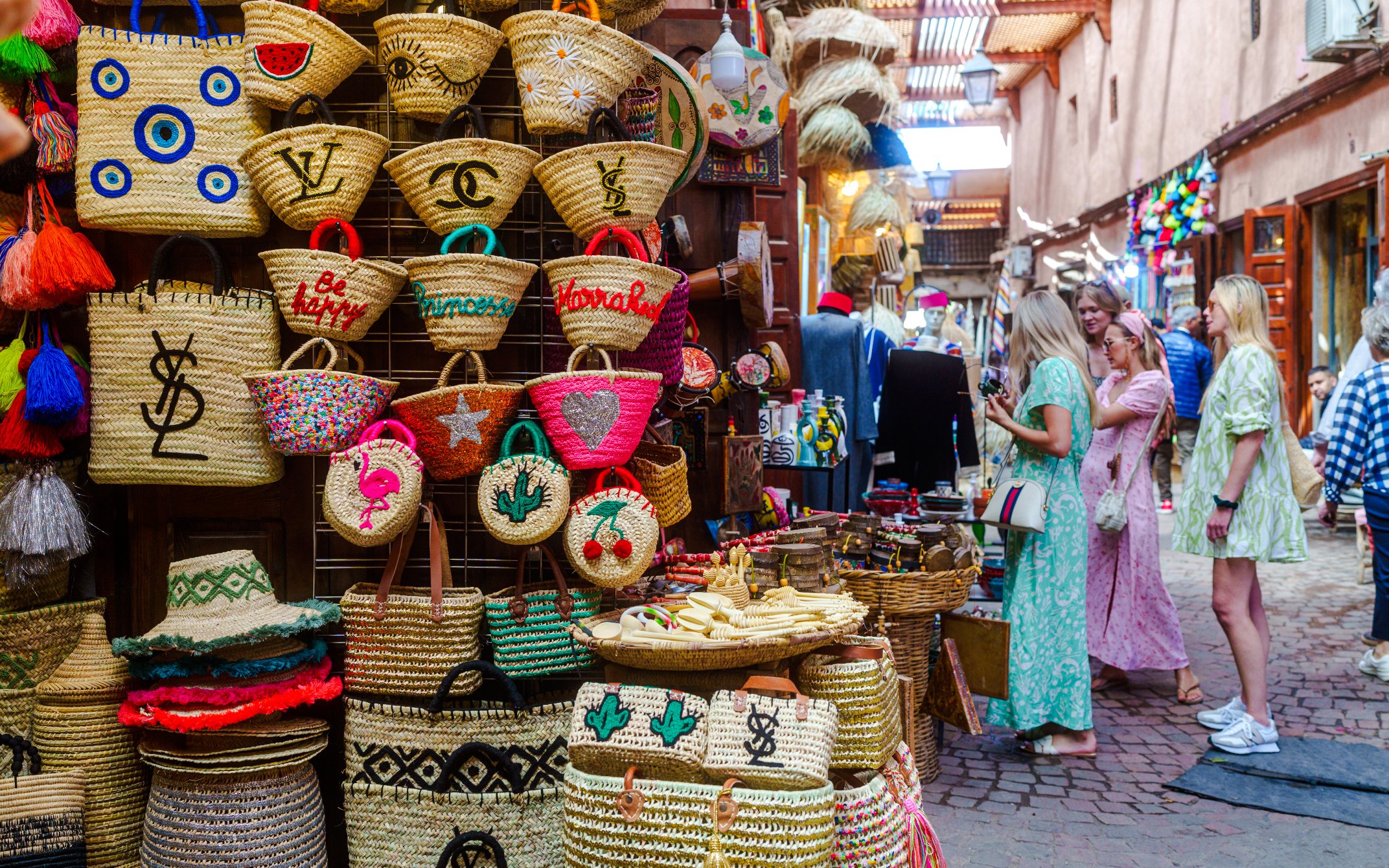 Visitors exploring colorful woven baskets in Marrakech souks.