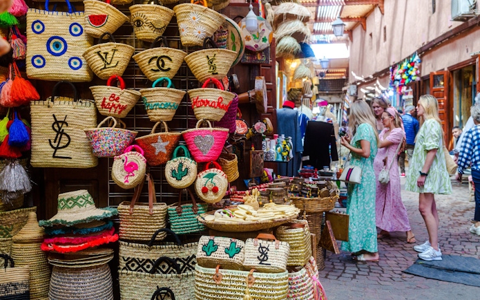 Visitors exploring colorful woven baskets in Marrakech souks.