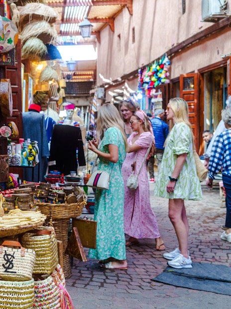 Visitors exploring colorful woven baskets in Marrakech souks.