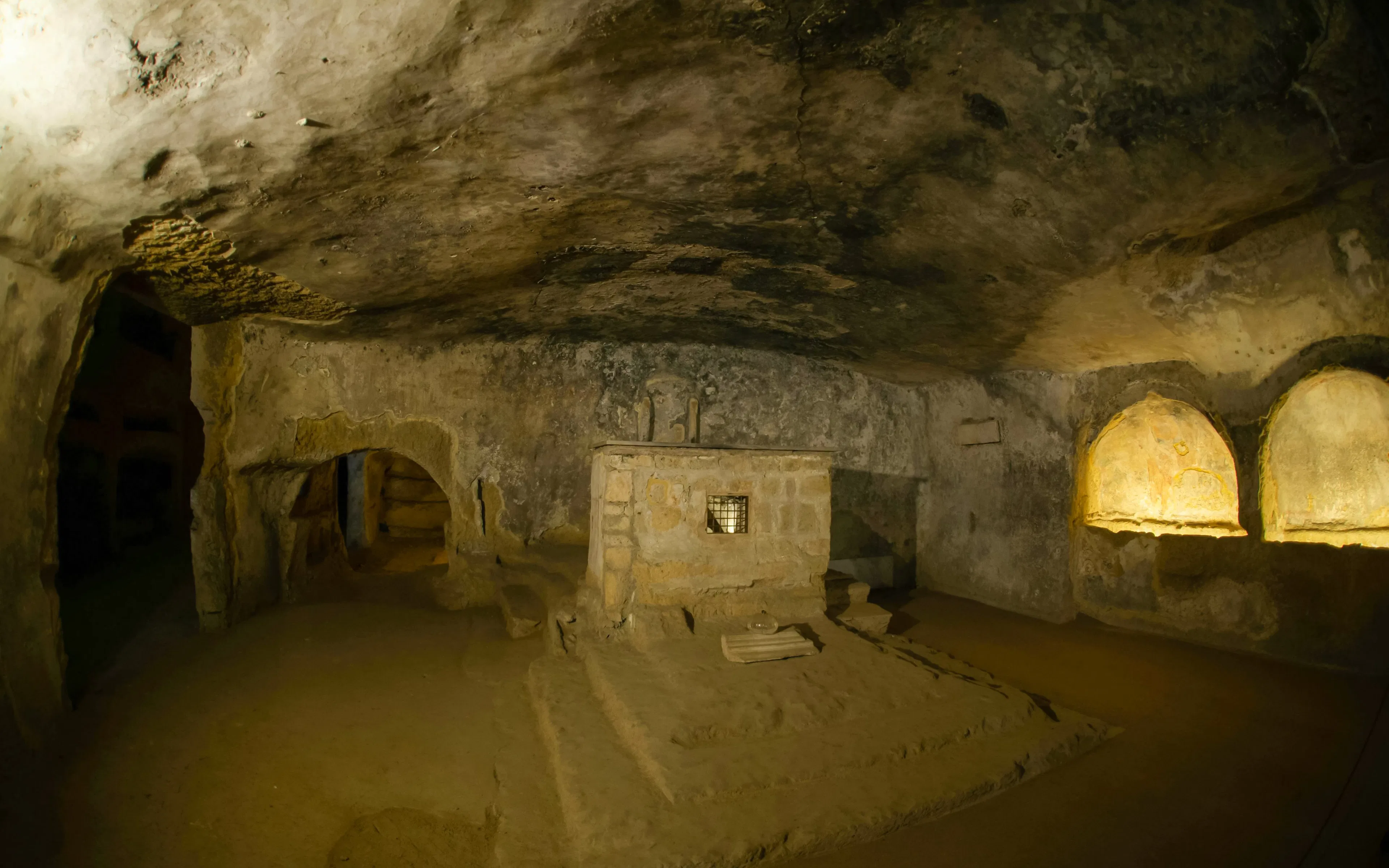 Catacombs of San Gennaro interior with ancient stone altar and arched niches.