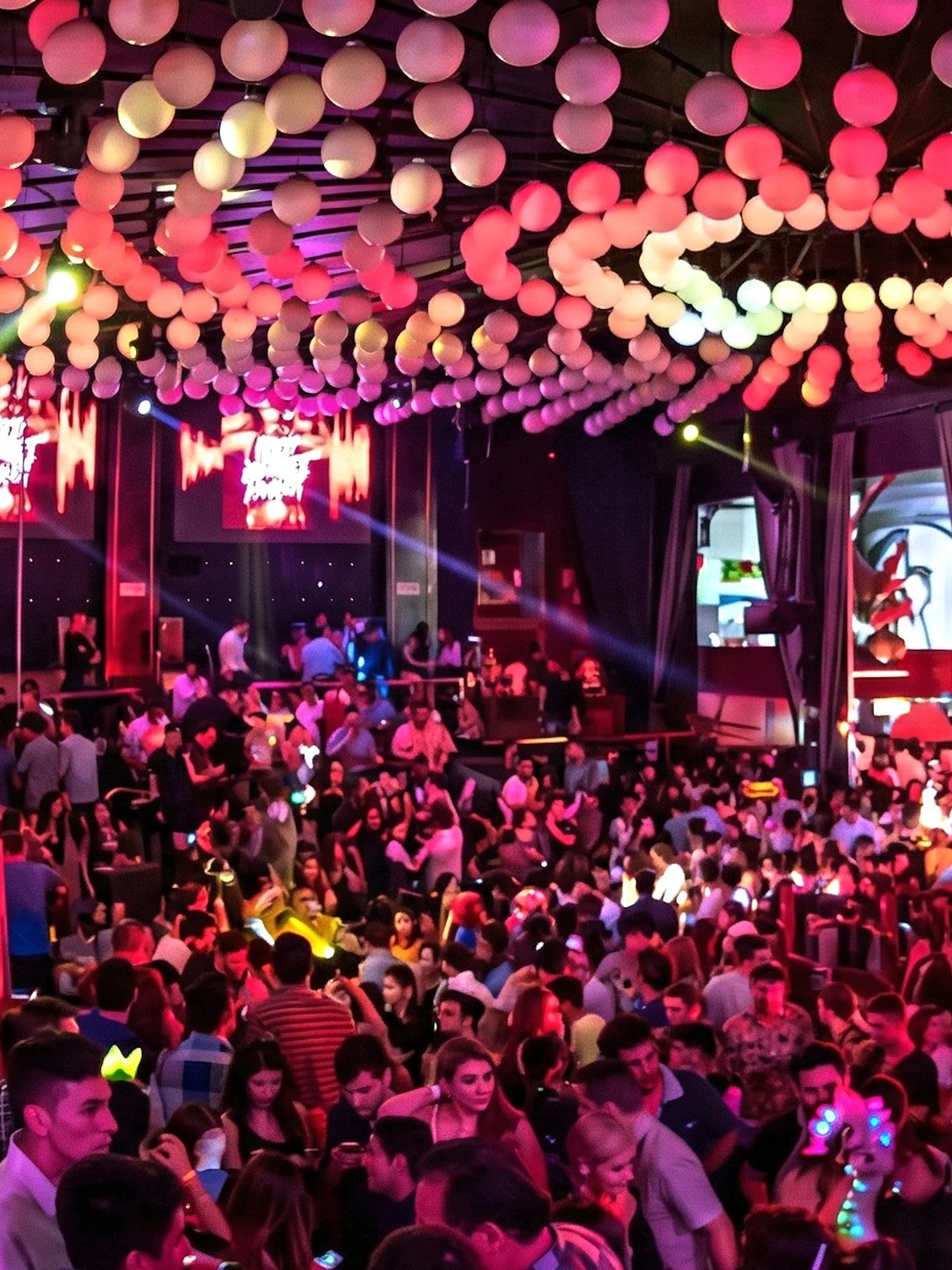 Crowded dance floor at Mandala Nightclub in Cancun with vibrant lighting and decorations.