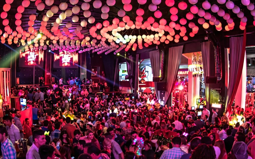 Crowded dance floor at Mandala Nightclub in Cancun with vibrant lighting and decorations.