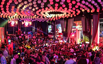 Crowded dance floor at Mandala Nightclub in Cancun with vibrant lighting and decorations.