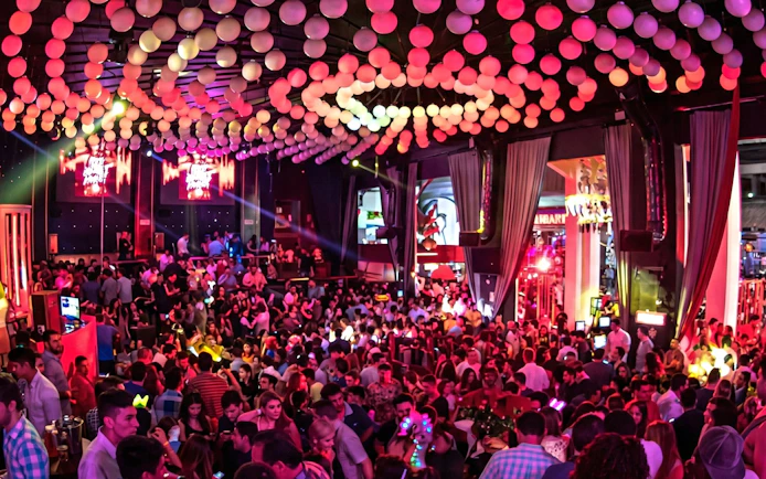 Crowded dance floor at Mandala Nightclub in Cancun with vibrant lighting and decorations.