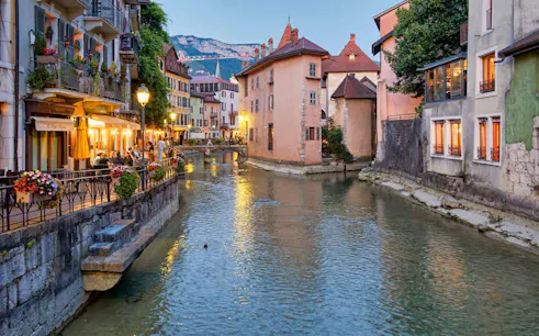 Canal view in Annecy Old Town with historic buildings and outdoor dining.