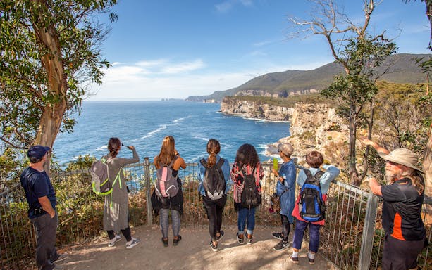 Group overlooking cliffs and ocean on Port Arthur tour, Tasmania.