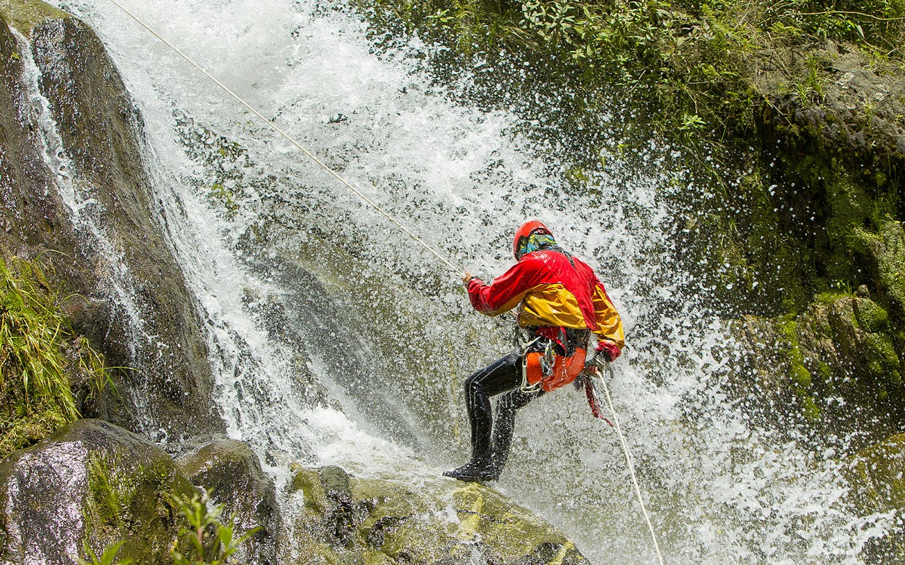 Canyoning in Varziela River, Castro Laboreiro, person rappelling down waterfall.