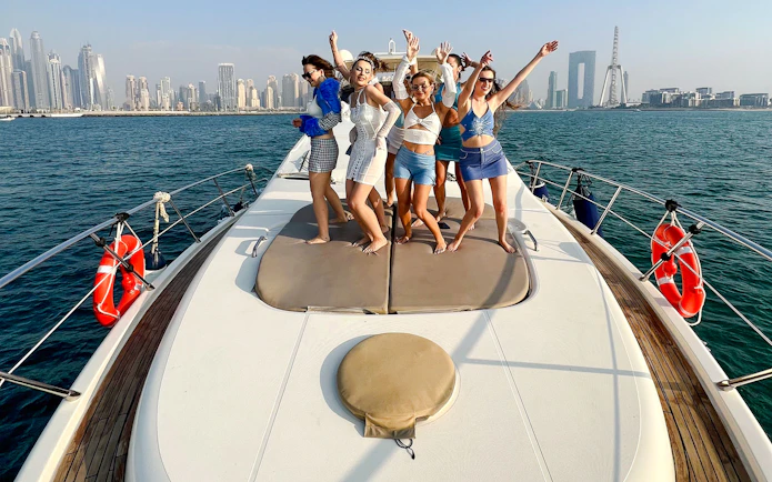 Tourists dancing on a luxury yacht with Dubai skyline in the background.