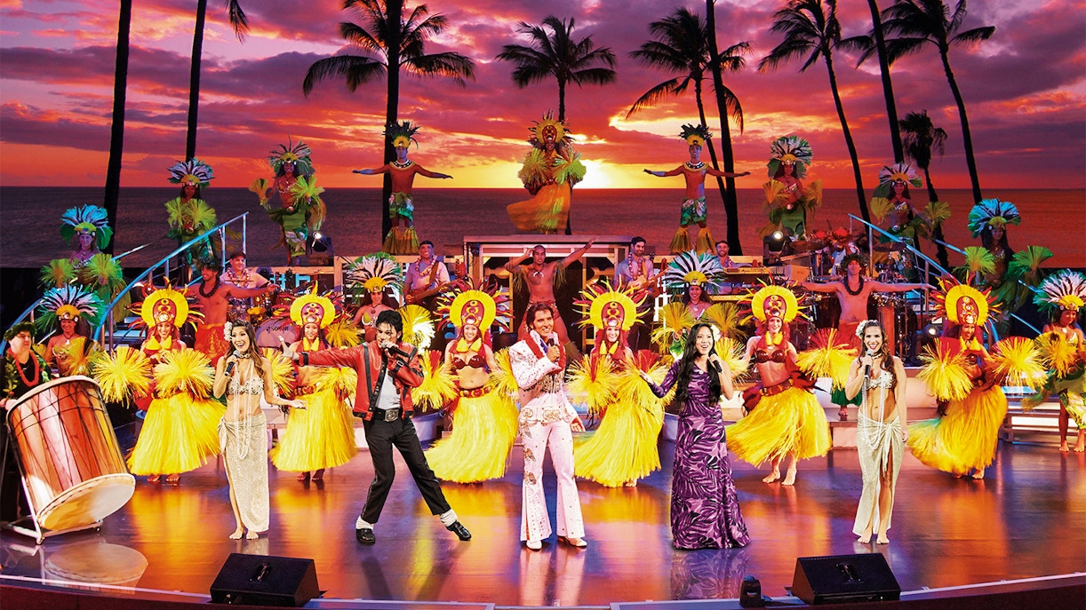 Performers on stage at Rock-A-Hula Show with dancers and musicians in Hawaiian attire.