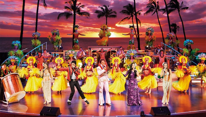 Performers on stage at Rock-A-Hula Show with dancers and musicians in Hawaiian attire.