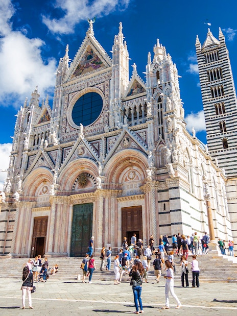 Siena Cathedral facade with visitors in Piazza del Duomo, Italy.