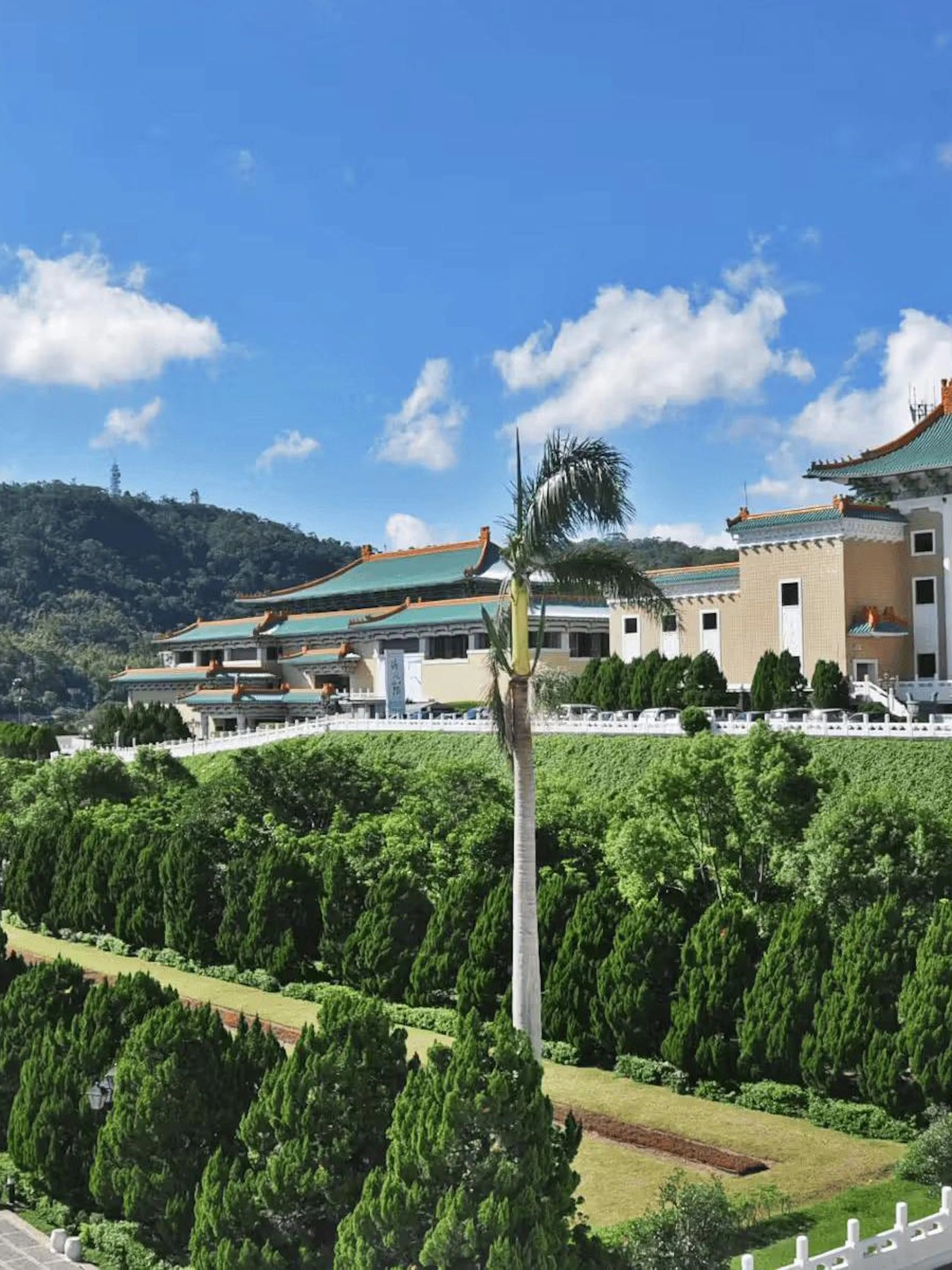 National Palace Museum in Taipei with lush gardens and distant mountains.