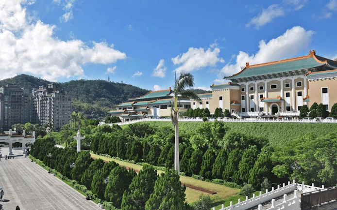 National Palace Museum in Taipei with lush gardens and distant mountains.