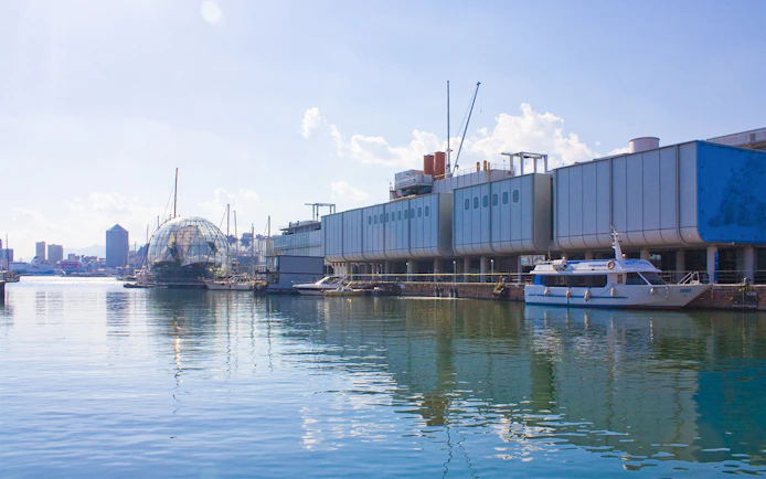 Aquarium of Genoa exterior with boats docked in the harbor, Italy.