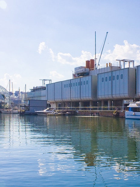 Aquarium of Genoa exterior with boats docked in the harbor, Italy.