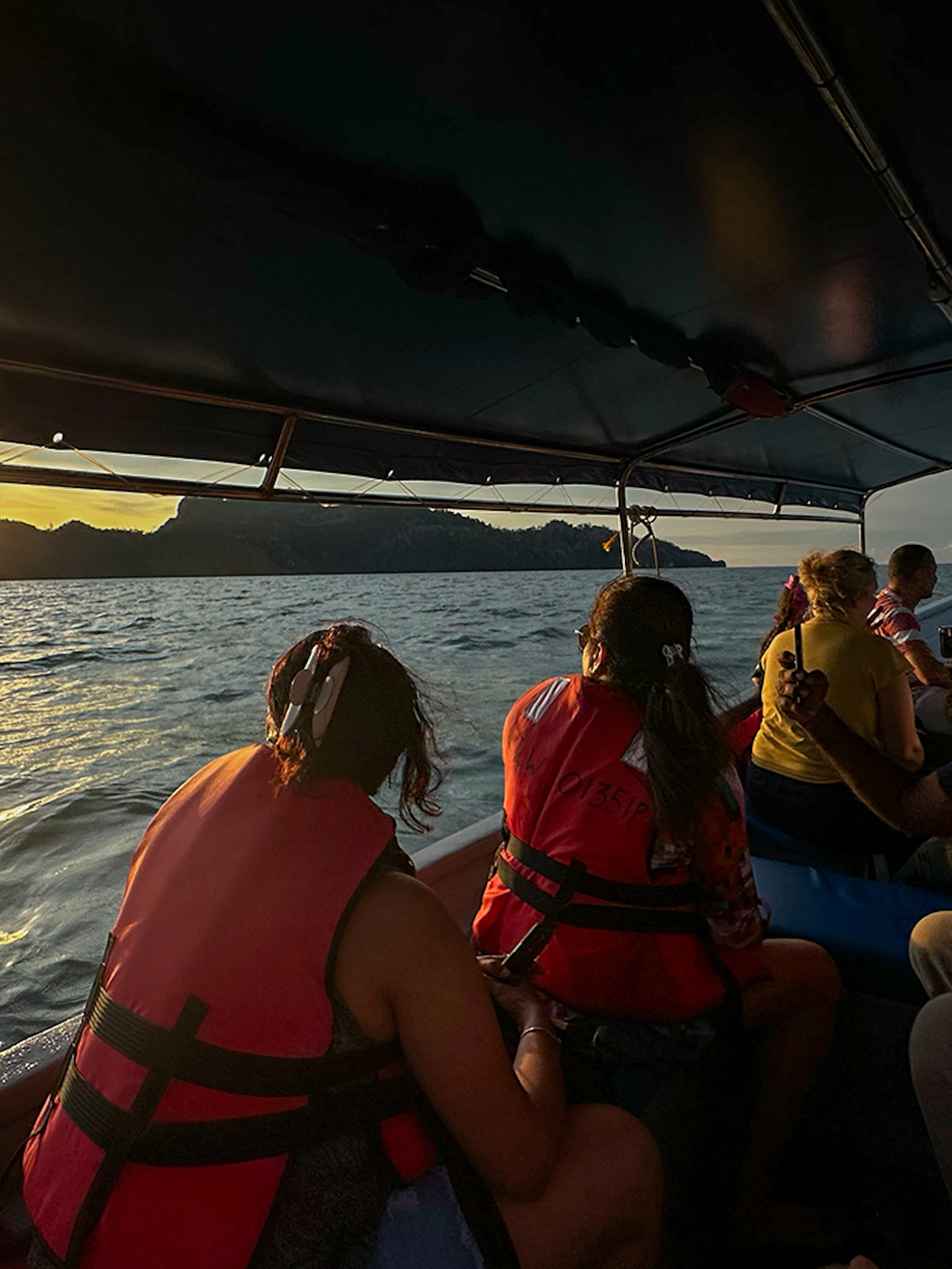 Passengers on boat watching sunset over water during Langkawi mangrove tour.