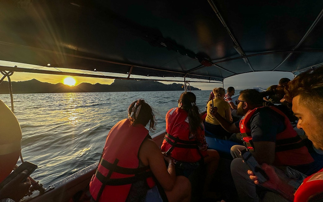 Passengers on boat watching sunset over water during Langkawi mangrove tour.