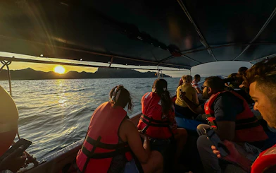 Passengers on boat watching sunset over water during Langkawi mangrove tour.