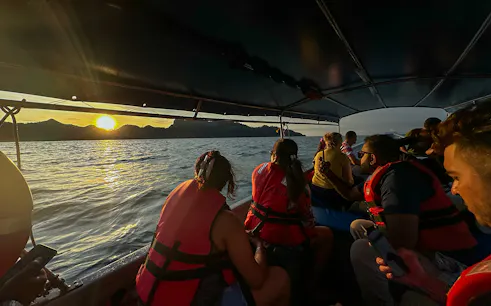 Passengers on boat watching sunset over water during Langkawi mangrove tour.