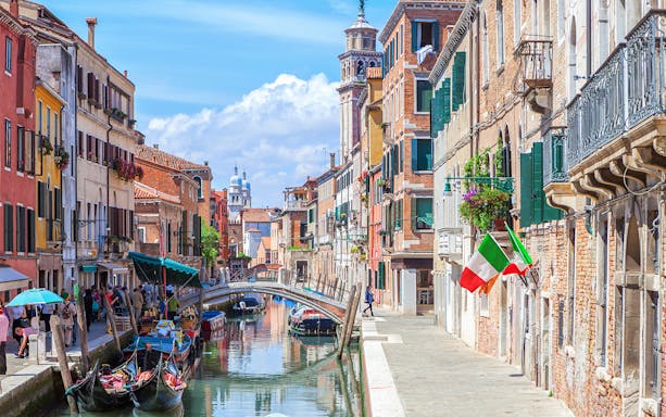 Venice canal with gondolas and colorful buildings on a walking tour route.