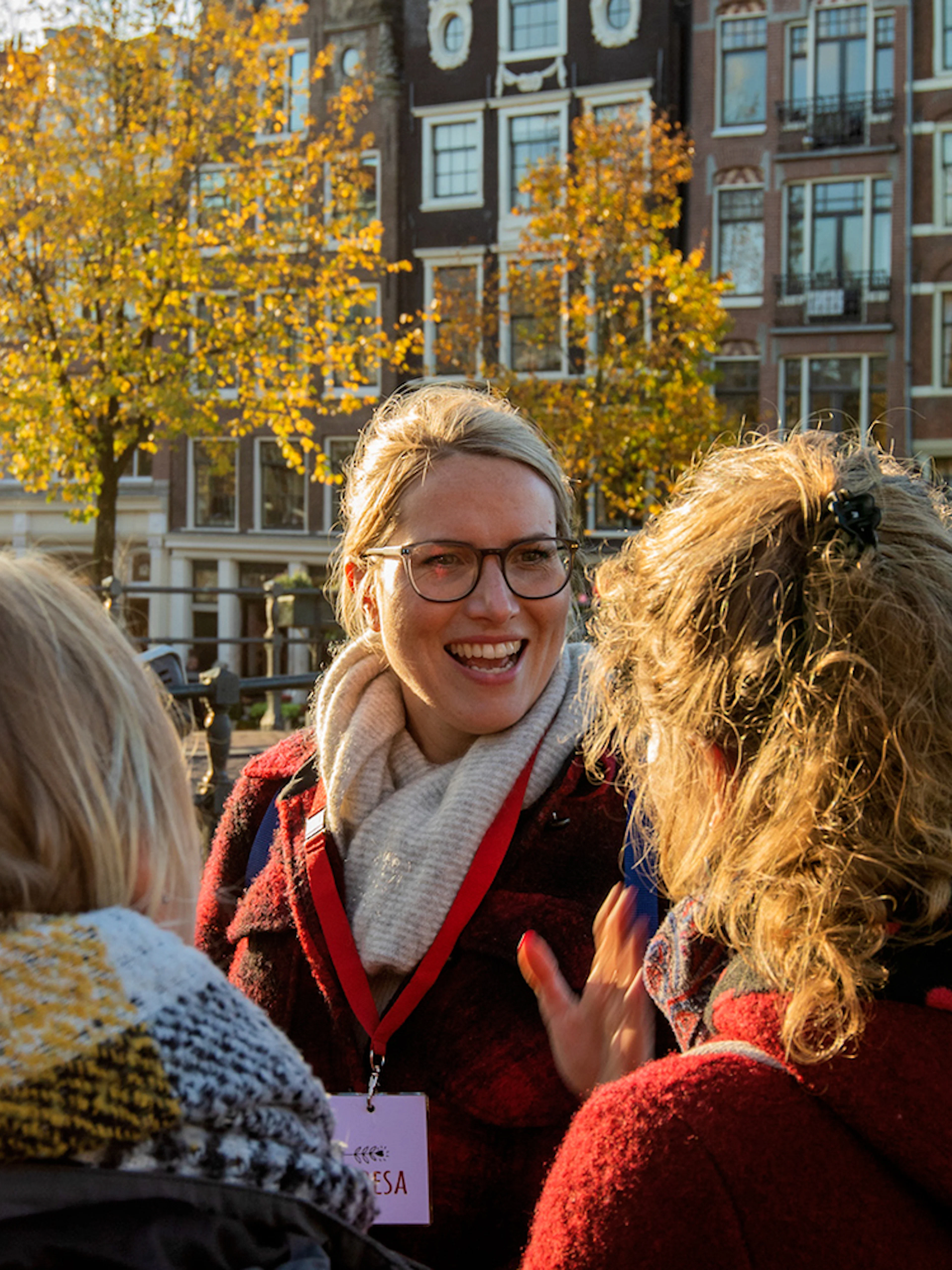 Tour guide leading a group in Amsterdam with historic canal houses in the background.