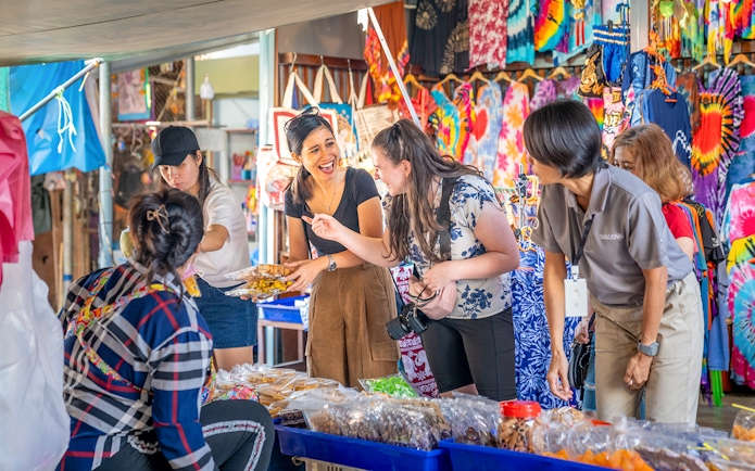 Tourists exploring food stalls at Damnoen Saduak Floating Market, Thailand.