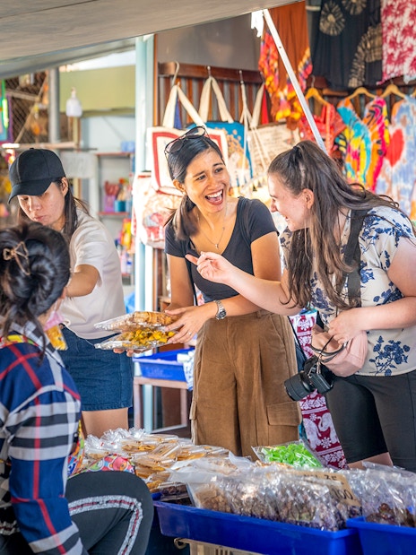 Tourists exploring food stalls at Damnoen Saduak Floating Market, Thailand.