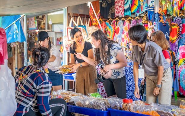 Tourists exploring food stalls at Damnoen Saduak Floating Market, Thailand.