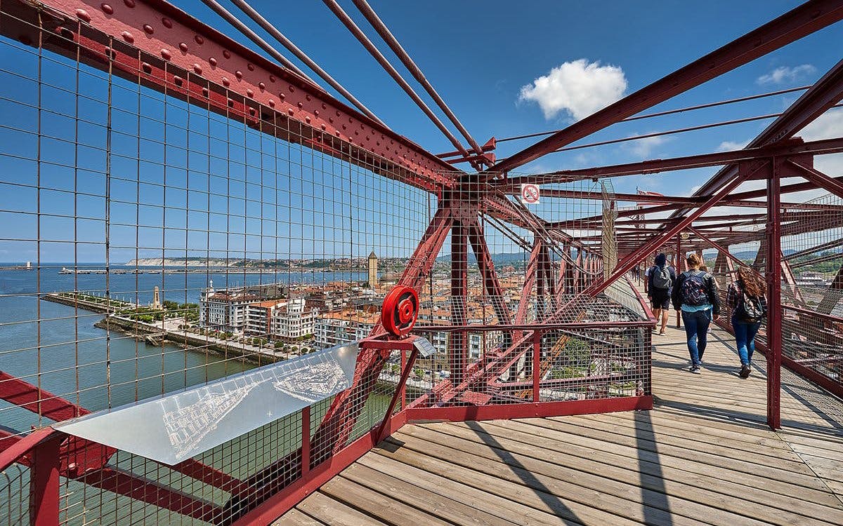 Visitors walking on Biscay Bridge with city and river views in Portugalete, Spain.