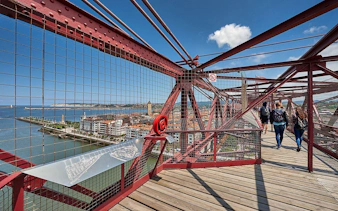 Visitors walking on Biscay Bridge with city and river views in Portugalete, Spain.