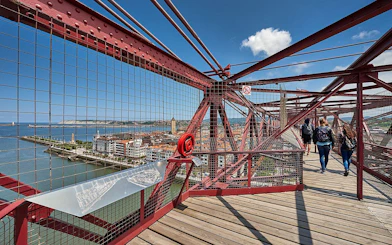 Visitors walking on Biscay Bridge with city and river views in Portugalete, Spain.