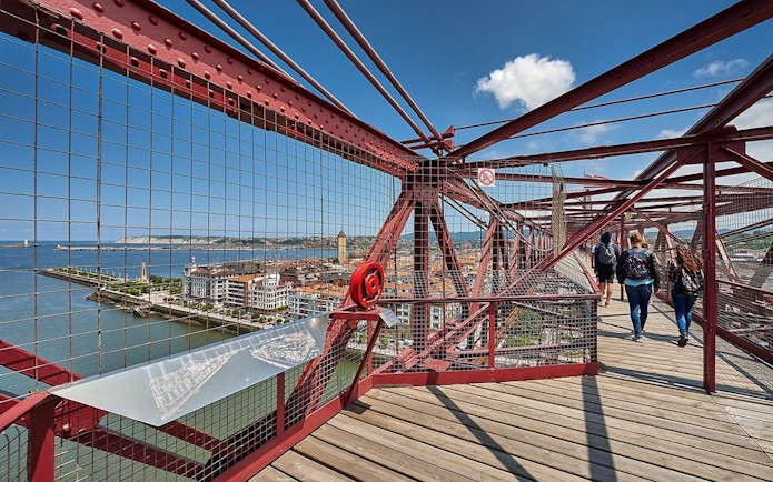 Visitors walking on Biscay Bridge with city and river views in Portugalete, Spain.