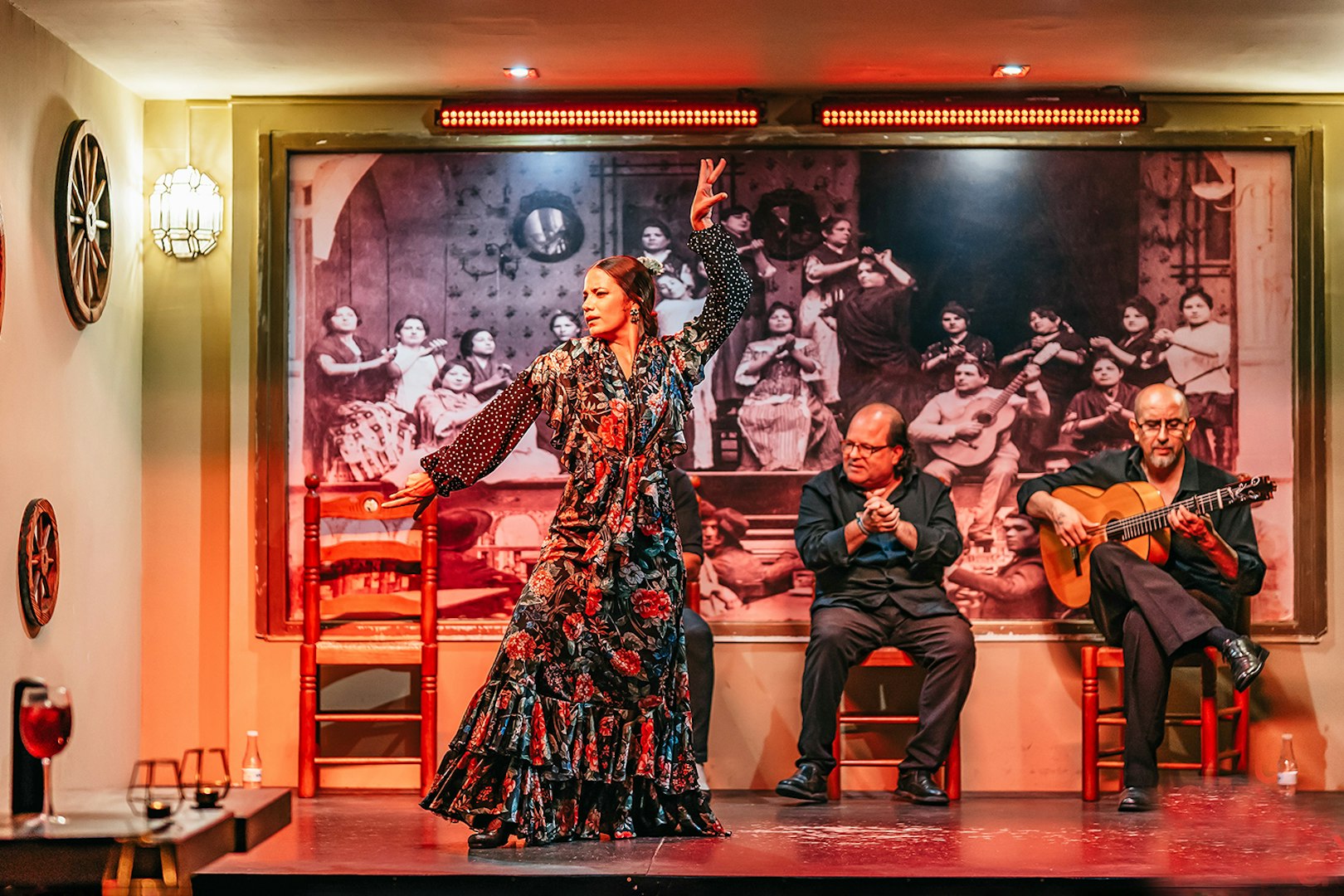 Flamenco dancer performing with musicians in a vibrant show, drink on table, Spain.