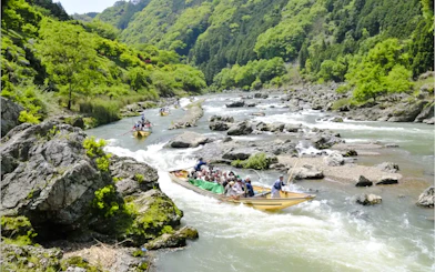 Boat tour on Hozugawa River with lush greenery and rocky landscape, Kyoto.