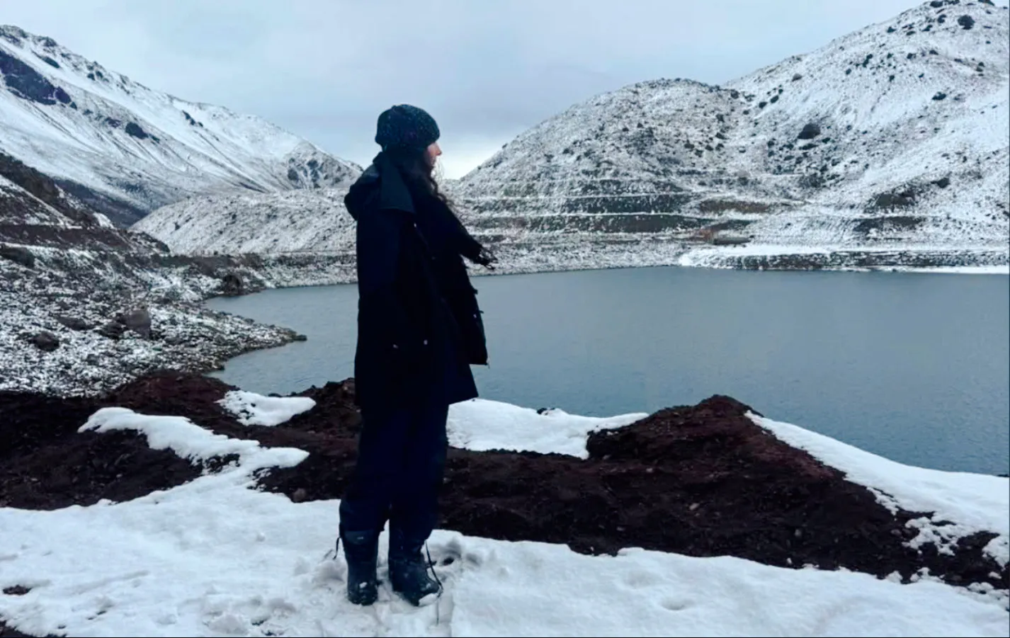 Person standing by snow-covered Embalse del Yeso in Cajón del Maipo, Santiago.