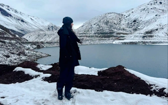 Person standing by snow-covered Embalse del Yeso in Cajón del Maipo, Santiago.