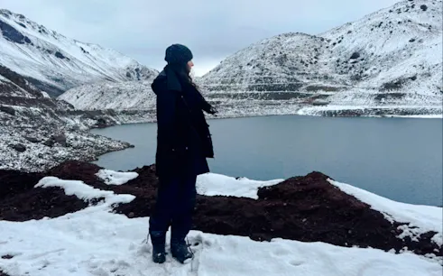 Person standing by snow-covered Embalse del Yeso in Cajón del Maipo, Santiago.