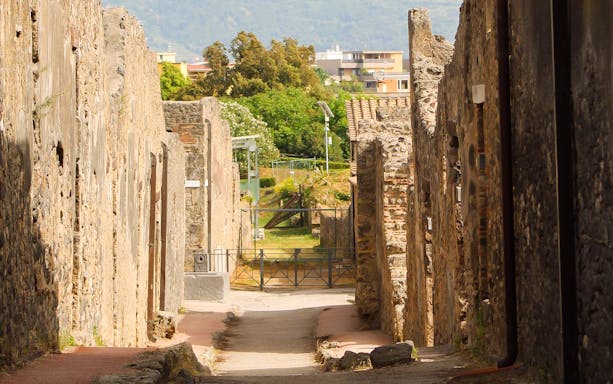 Ancient street in Pompeii with stone ruins, part of a tour from Rome to Naples.