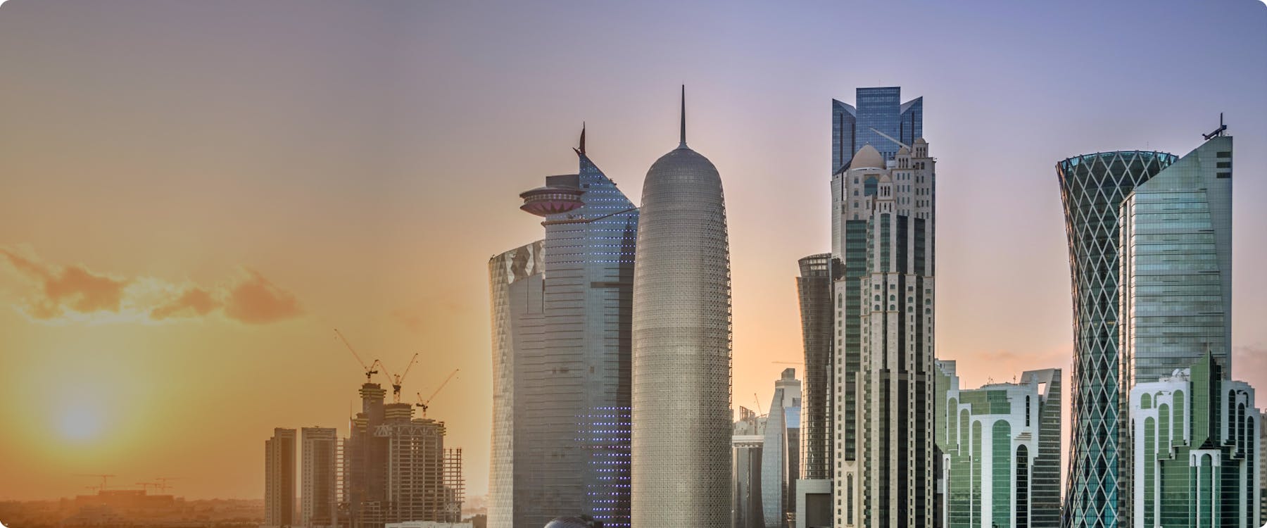 Doha skyline with modern skyscrapers at sunset.