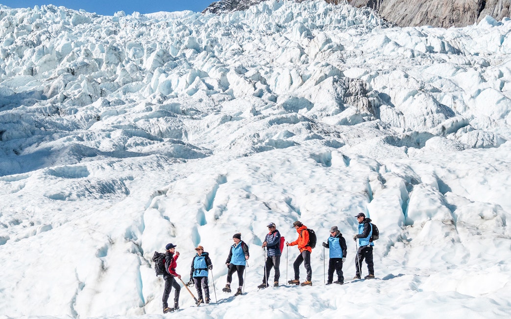 Group hiking on Fox Glacier during guided helicopter tour in New Zealand.