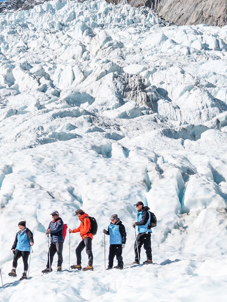 Group hiking on Fox Glacier during guided helicopter tour in New Zealand.